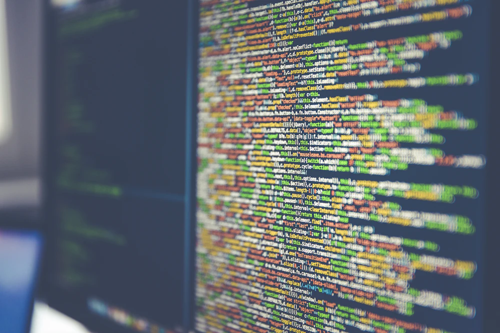 Developer working with code on dual-monitor setup